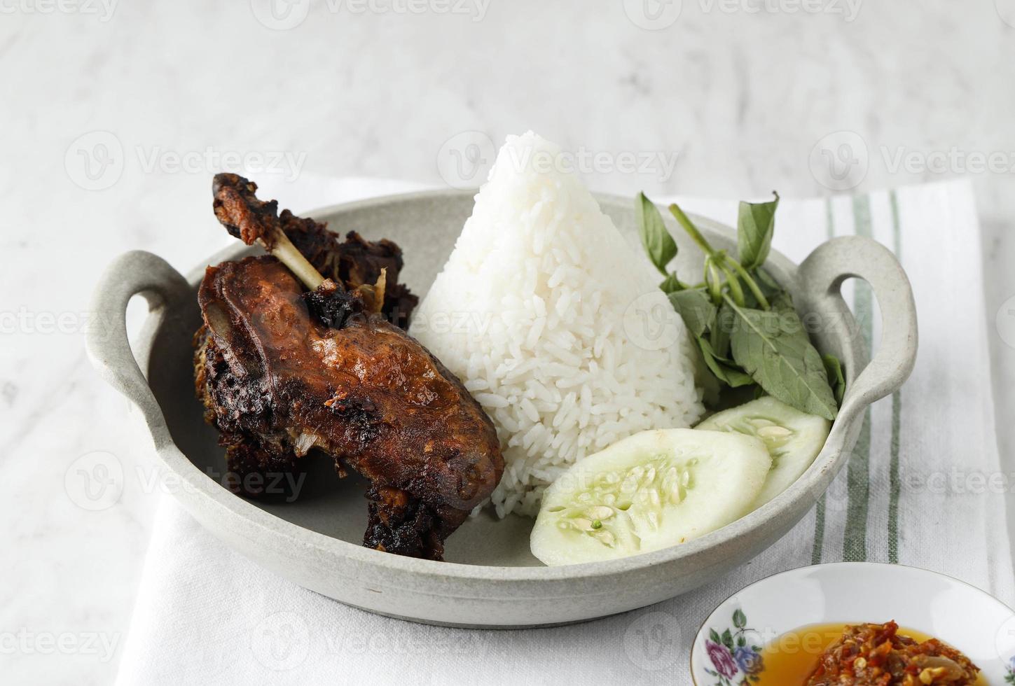 bebek ireng madura ou comida de rua típica de pato preto em surabaya, leste de java, indonésia. servido com arroz branco quente em forma de cone e sambal foto