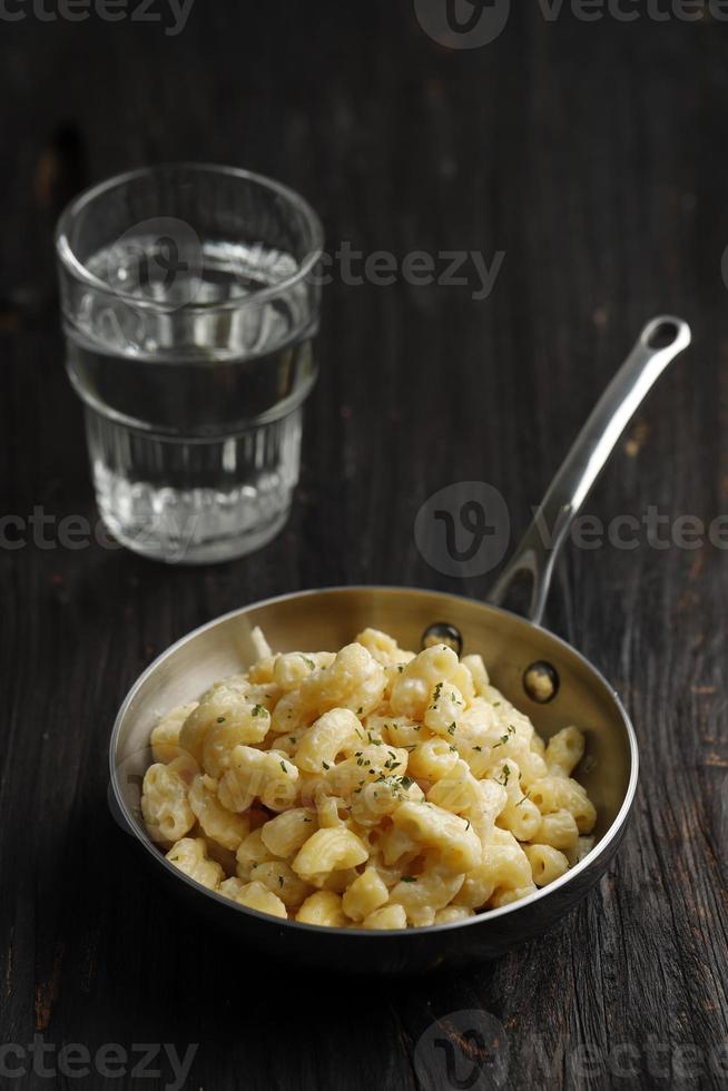 mac and cheese, macarrão de estilo americano com molho de queijo e cobertura de migalhas de pão crocante na mesa rústica escura foto