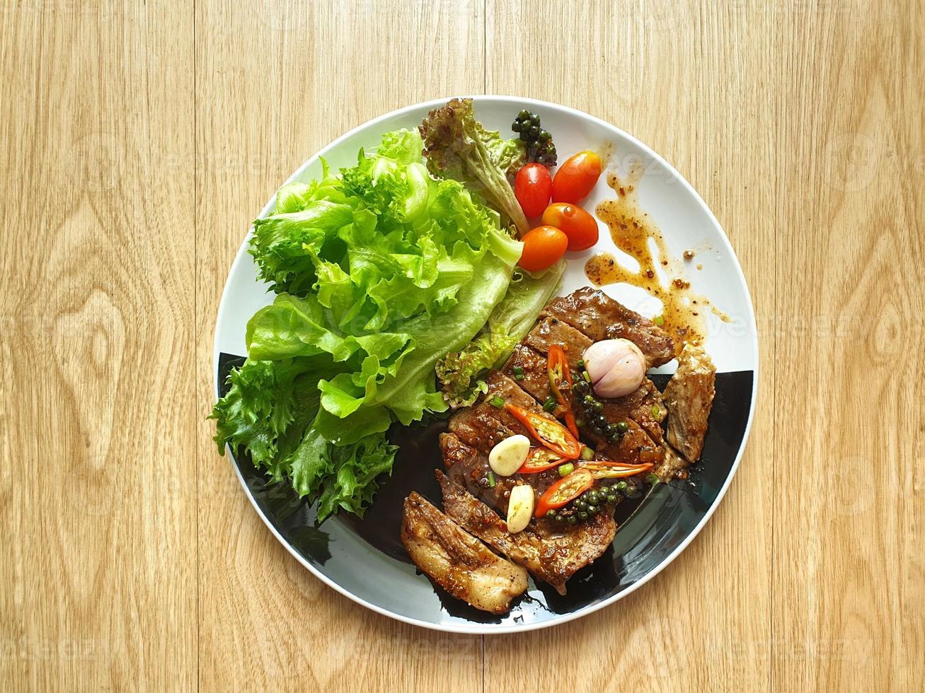 bife de porco grelhado com salada no prato preto e branco. mesa de madeira. receita de dieta cetogênica ou atkins. baixo carboidrato, alto teor de gordura. Vegetais frescos. tendência de comida saudável. para pacientes com diabetes. isolado. foto