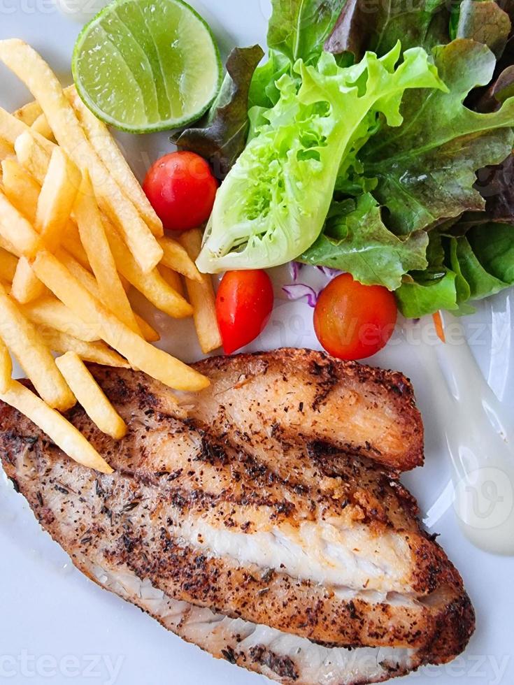 bife de peixe e batata frita com salada de vegetais verdes e limão. cozinha de frutos do mar com ômega. foto