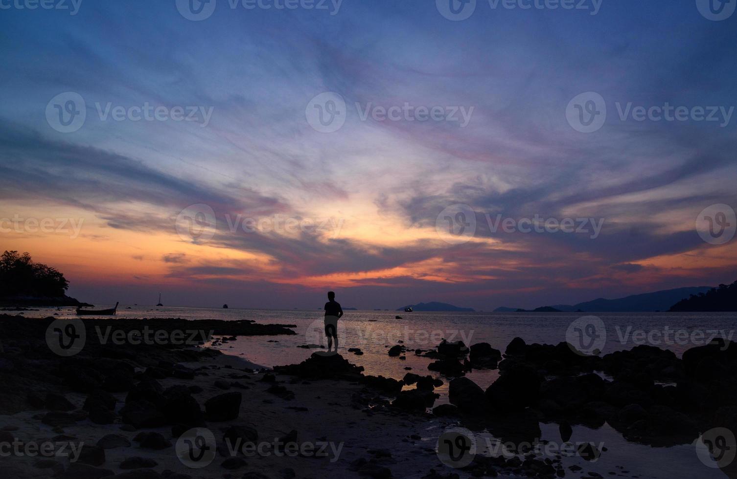 cena do belo pôr do sol e silhueta de um homem na praia foto