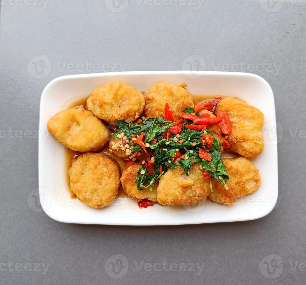 nuggets de manjericão quente e picante em um prato branco, comida tailandesa de fusão foto