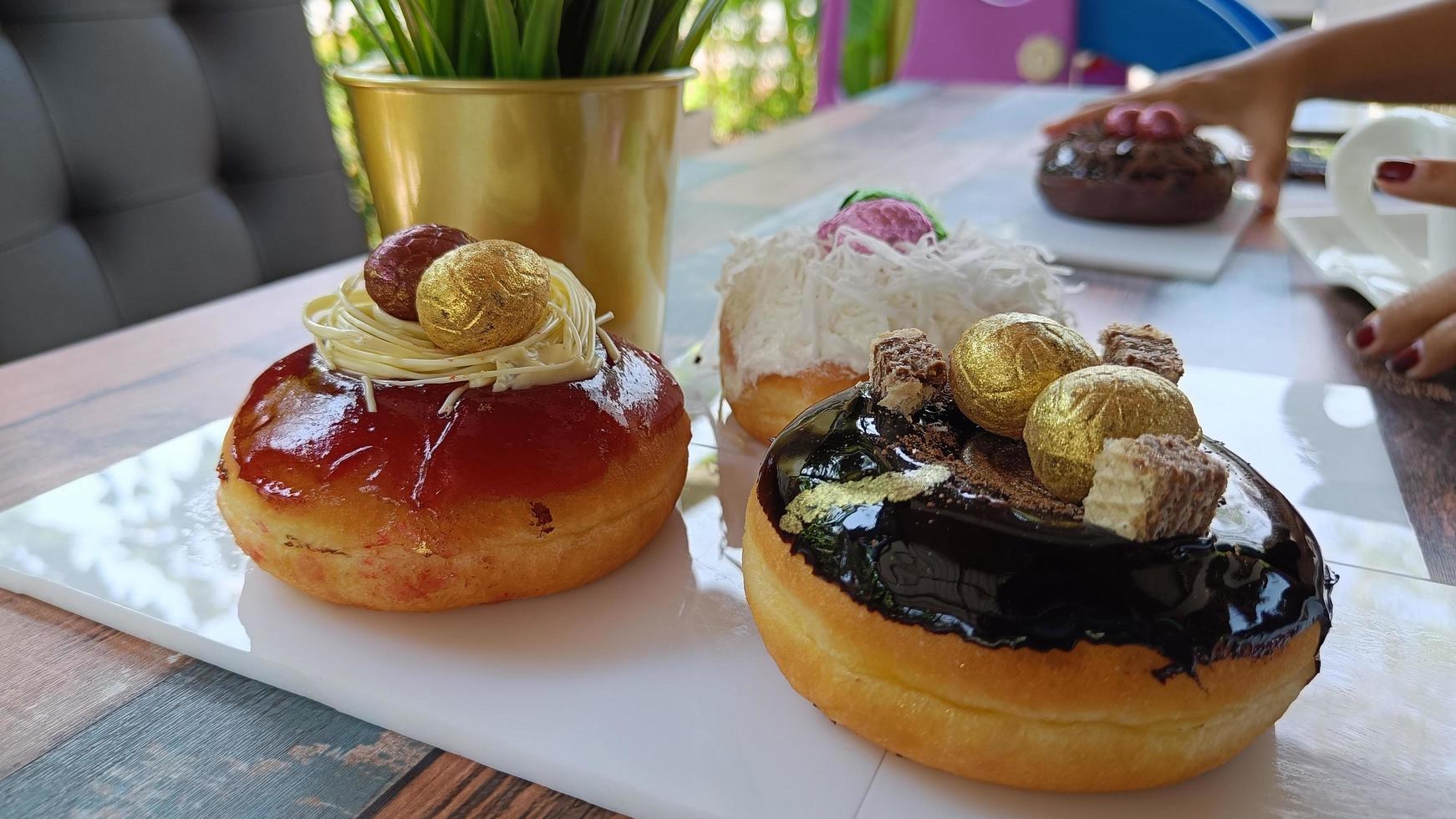 rosquinhas variadas com cobertura de chocolate, morango vitrificada e decorada com ovos de páscoa na chapa branca foto