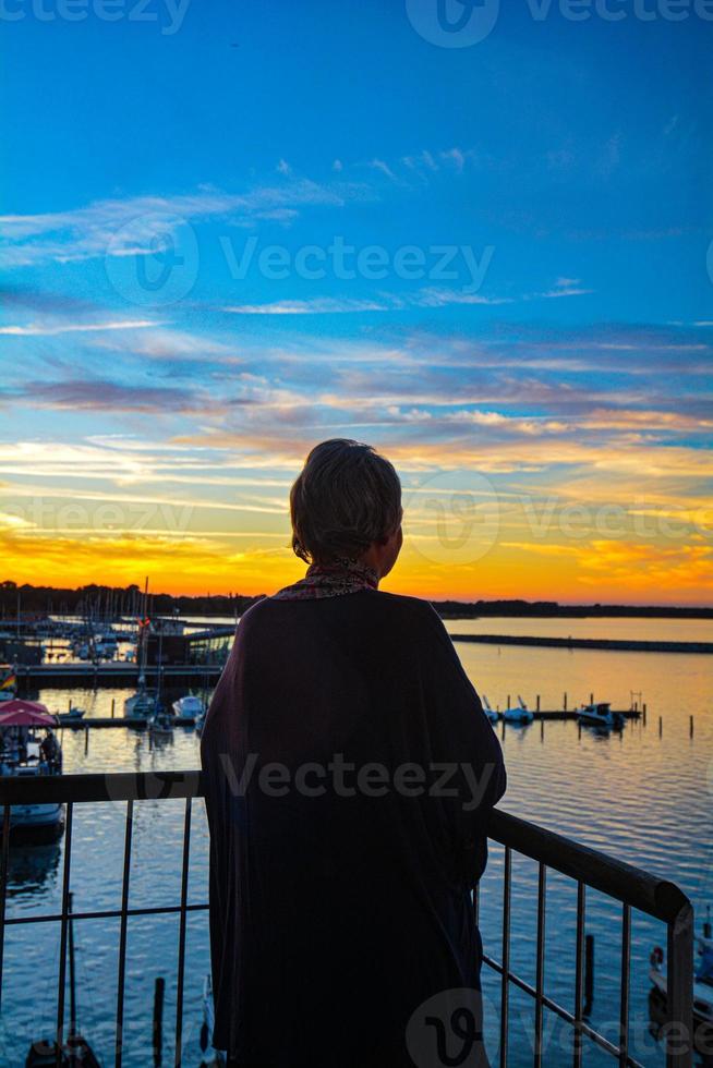 tiro panorâmico de uma silhueta por trás olhando para o lago e o lindo pôr do sol foto