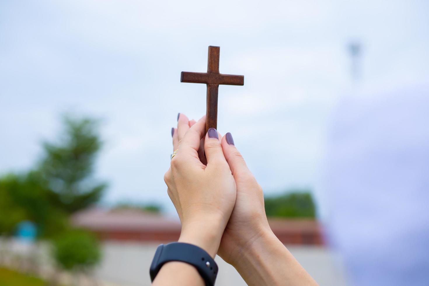 mãos de mulher enquanto rezava pela religião cristã, mulher casual rezando com uma cruz, conceito de religião. foto
