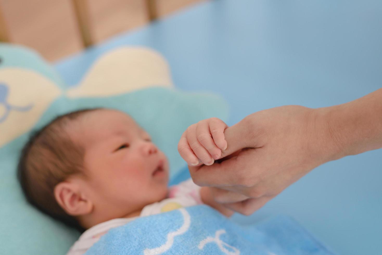 bebê recém-nascido asiático segurando a mão da mãe foto