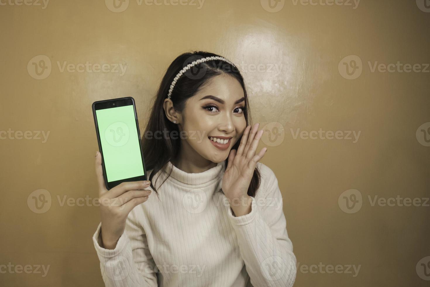 felizes e sorridentes jovens mulheres asiáticas mostrando uma tela verde em branco. foto