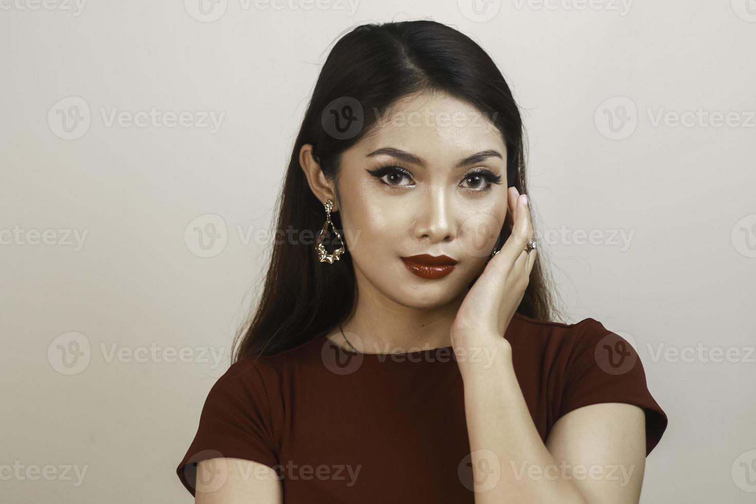 uma mulher asiática de aparência feroz em uma camisa vermelha posando na frente de fundo branco foto