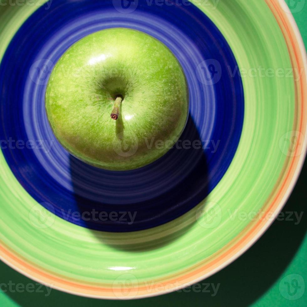 maçã verde na placa colorida com sombra escura. maçã verde vovó smith em um prato. foto