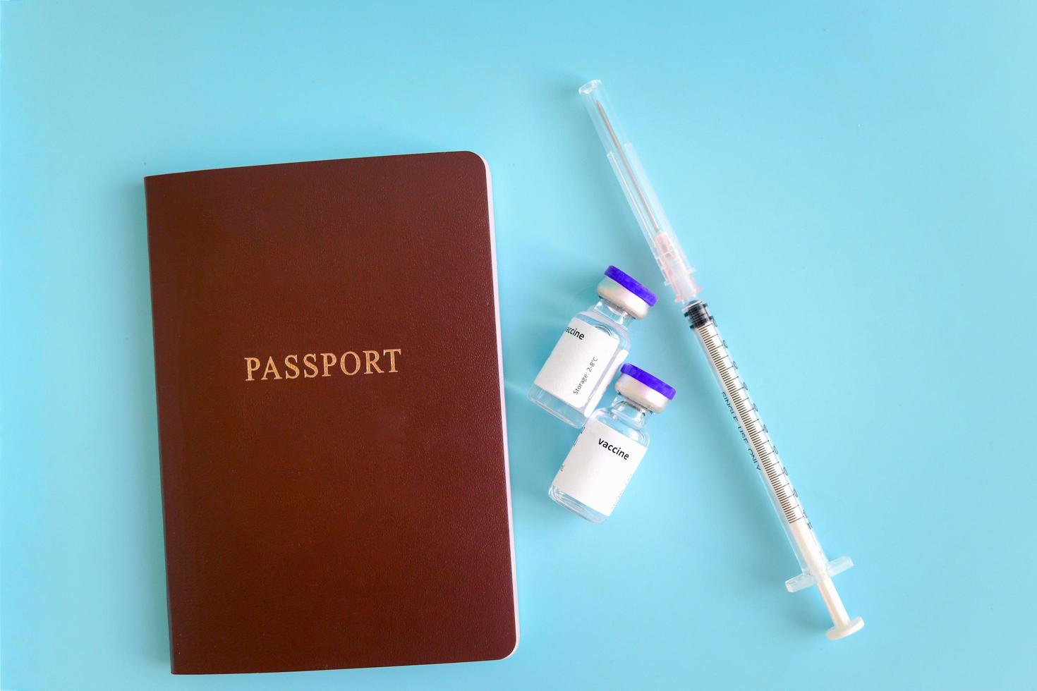 passaporte com frascos de vacina e seringa de agulha em fundo azul, viagem de segurança na viagem de férias do viajante que foi vacinado com a vacina coronavírus covid-19. foto
