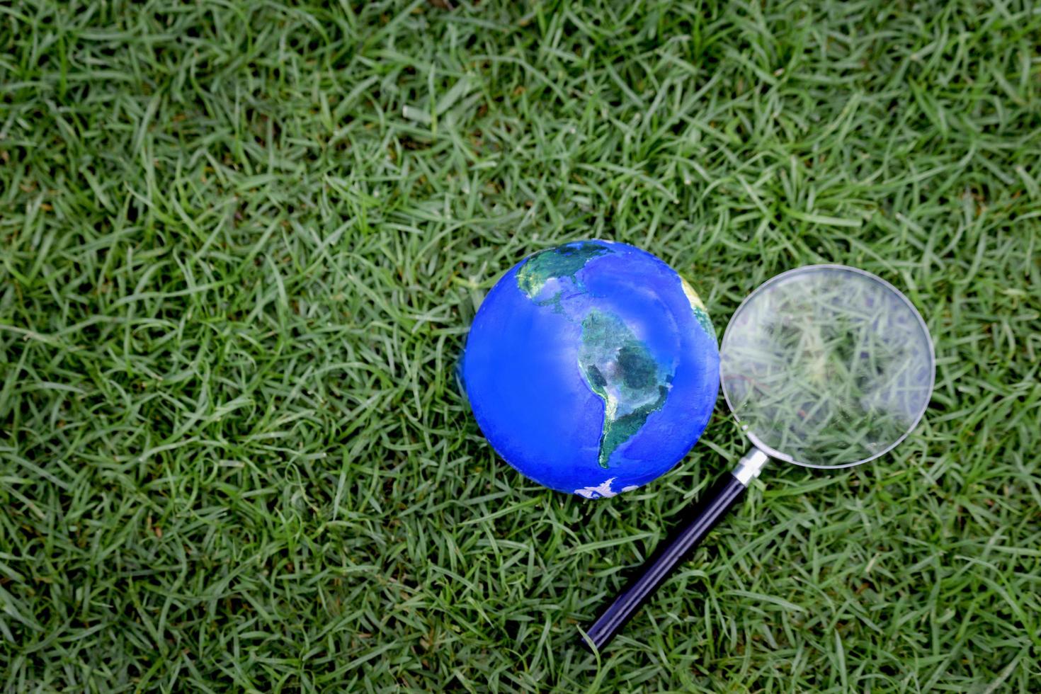 globo da terra com lupa na grama verde, descobrindo coisas novas em nosso planeta, interessado na natureza e no mundo foto