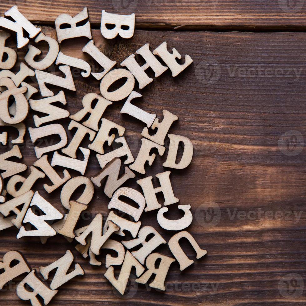 letras do alfabeto inglês em um fundo escuro de madeira. o conceito de educação, jogos de palavras, bordado. espaço para texto foto