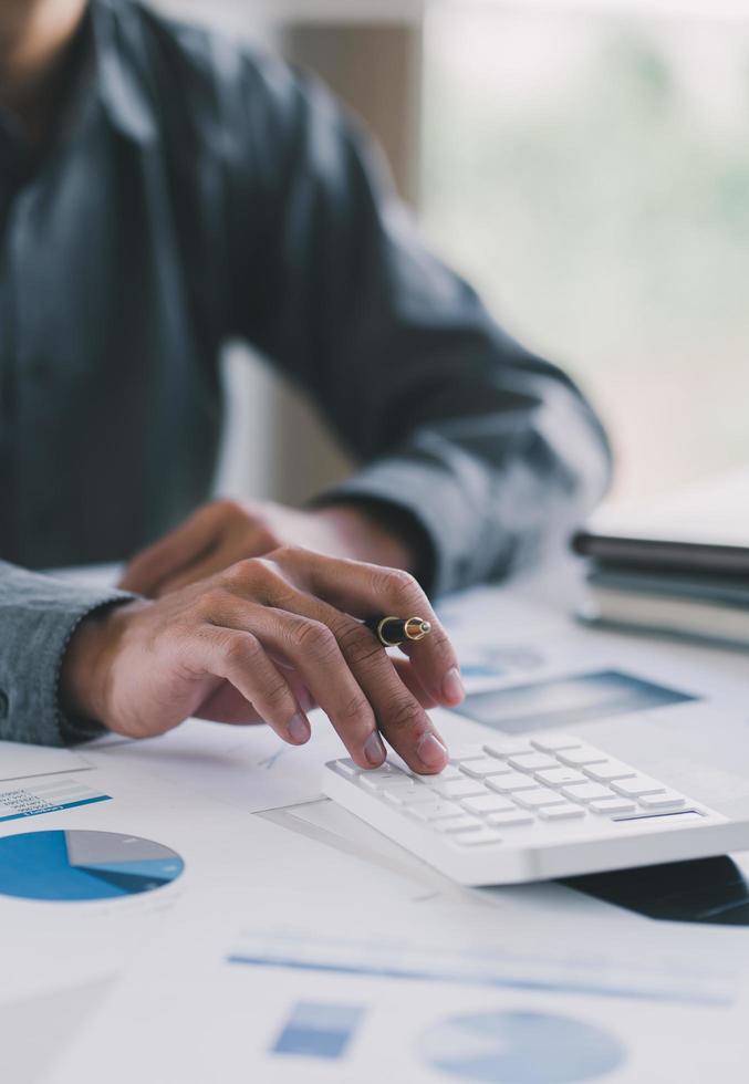 feche as mãos do homem de negócios usando a calculadora contando a conta financeira do imposto. mãos de homem calculando número, dados, gráfico, contabilidade de planejamento de auditoria de gráfico no relatório de negócios. conceito financeiro de auditoria fiscal. foto