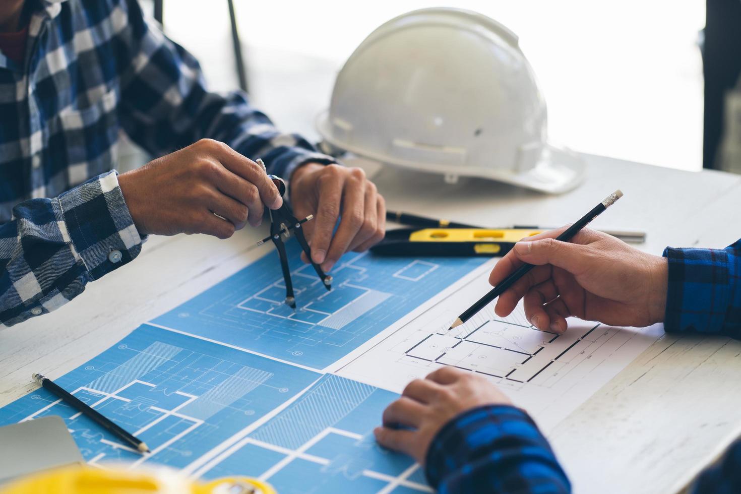 plano de desenho de mão de engenheiro da pessoa em impressão azul com equipamento de arquiteto, arquitetos discutindo na mesa, trabalho em equipe e conceito de construção de fluxo de trabalho. foto