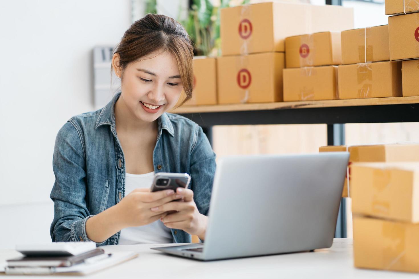 mulher embalando item que ela vende online. jovem start up pequeno empresário embalagem caixa de papelão no local de trabalho. vendedora freelancer prepara a caixa de encomendas do produto para entregar ao cliente. foto