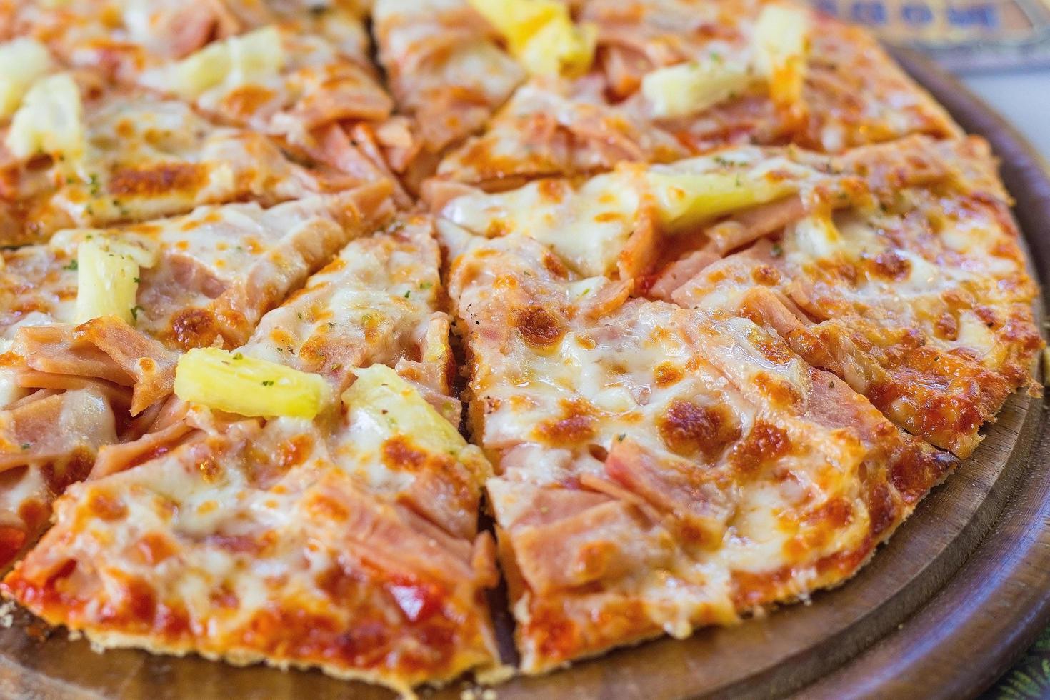 A pizza havaiana é uma comida italiana feita com molho de tomate, abacaxi picado, presunto e queijo. foto