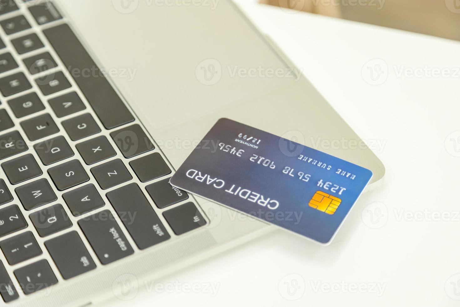 e-commerce, compras online e conceito de tecnologia. close-up de mock up cartão de crédito falso no computador portátil na mesa branca. foto