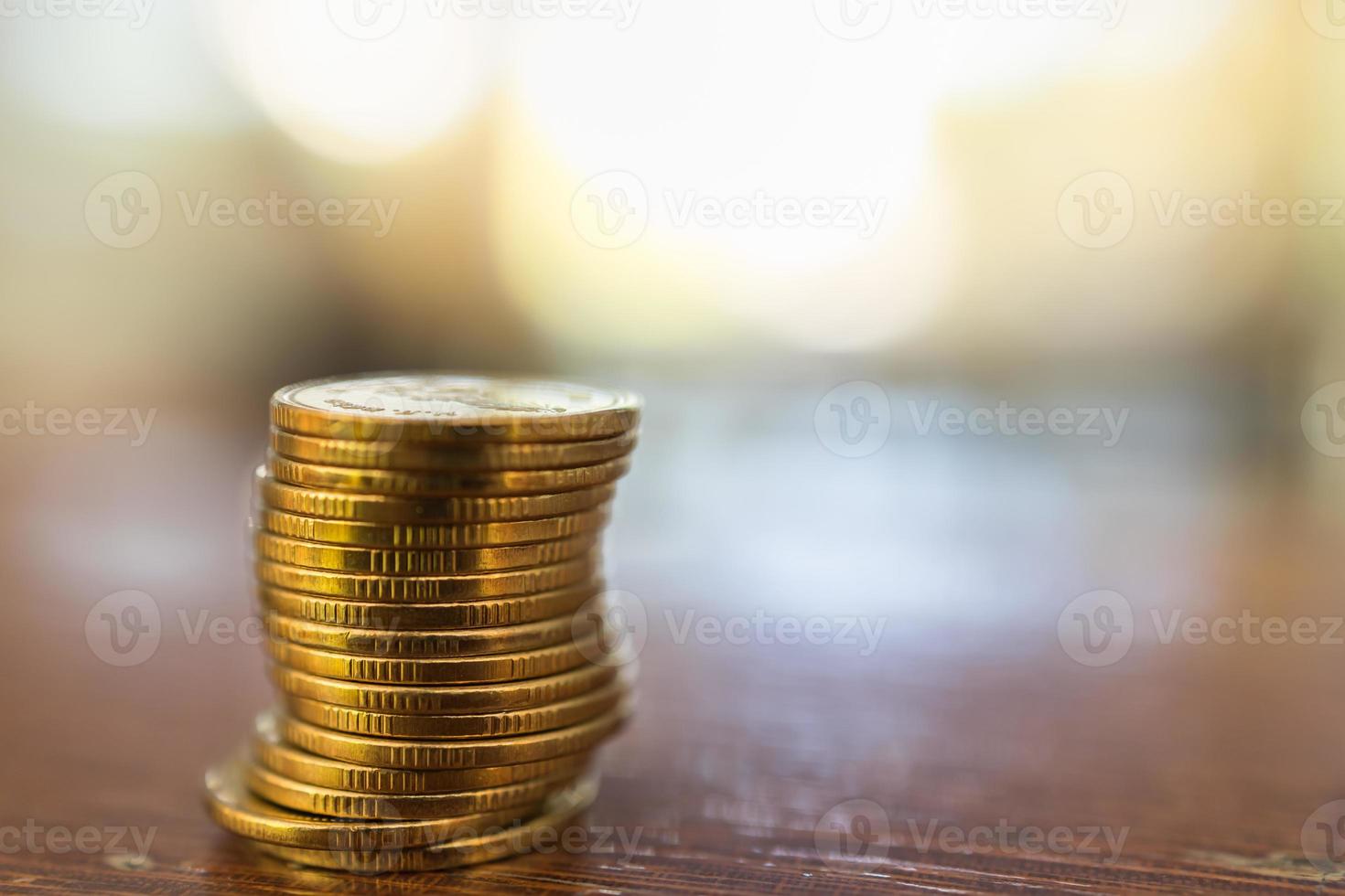 negócios, dinheiro, finanças, segurança e conceito de economia. feche a pilha de moedas de ouro na mesa de madeira sob a luz do sol com espaço de cópia. foto