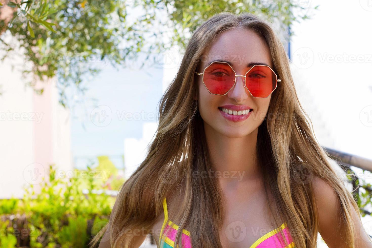 feche as férias de verão do rosto de mulher feliz. garota de sorriso de verão com cabelo loiro nas férias de verão em traje de banho. foco seletivo. óculos de sol rosa foto