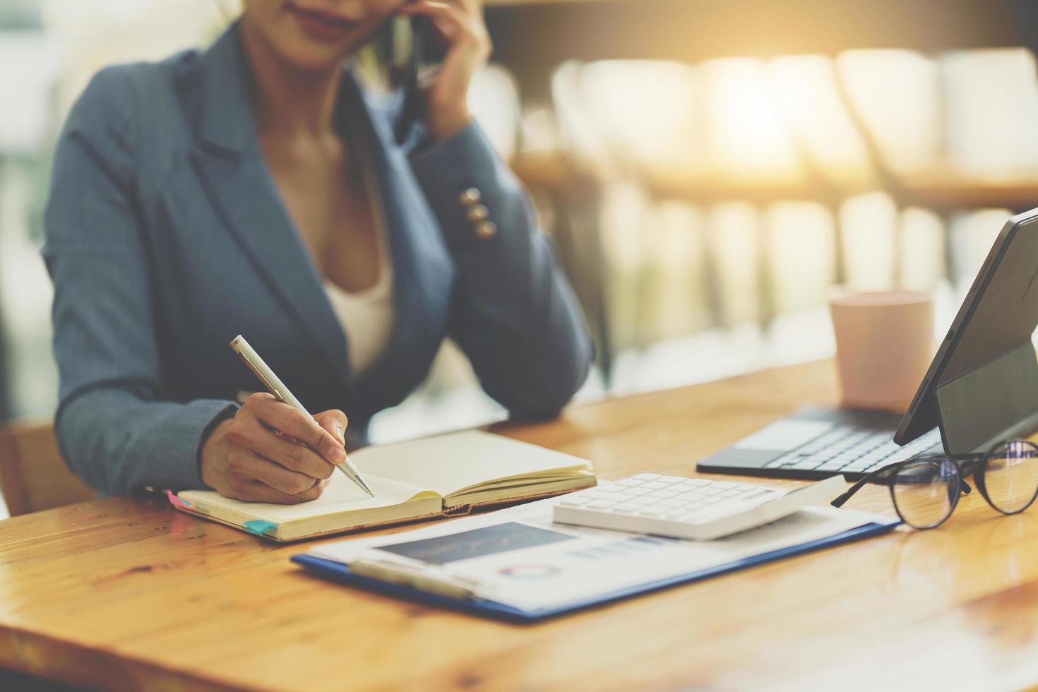 empresária asiática em terno formal no escritório feliz e alegre durante o uso de smartphone e trabalho foto