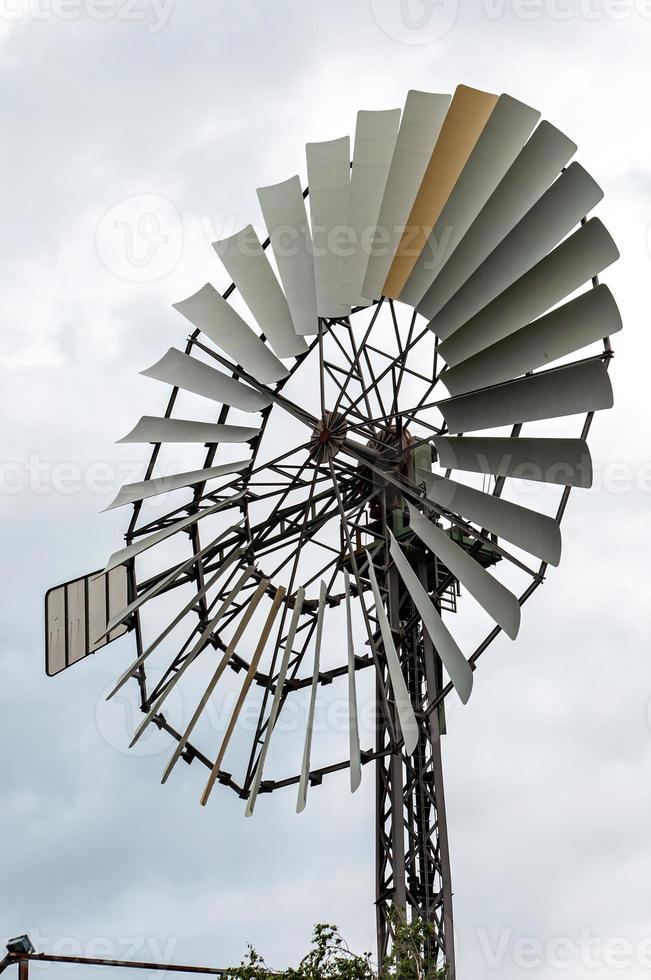 tiro vertical de uma turbina de moinho de vento antigo contra o céu nublado foto