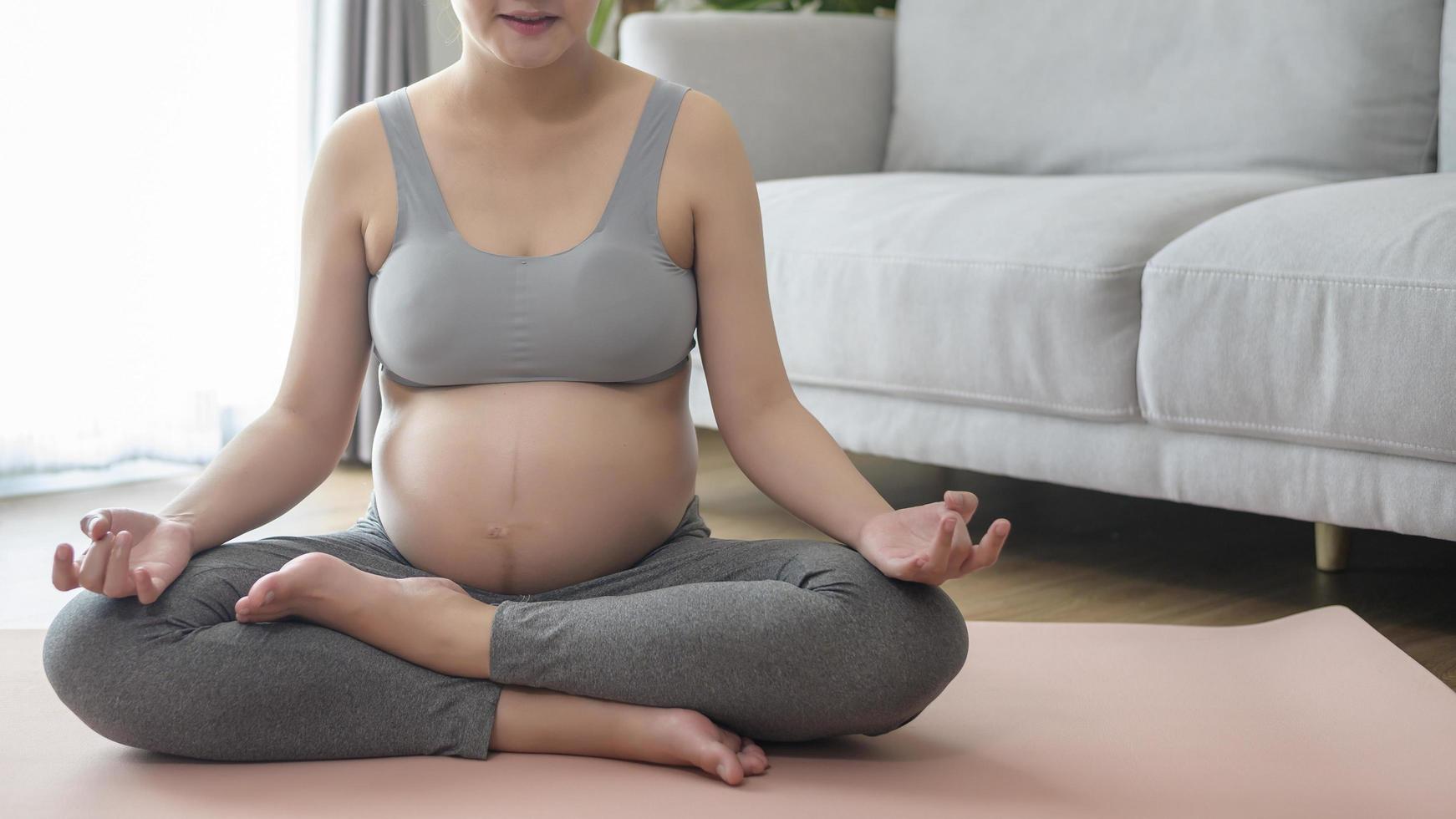 jovem mulher grávida fazendo ioga em casa, conceito de cuidados de saúde e gravidez foto