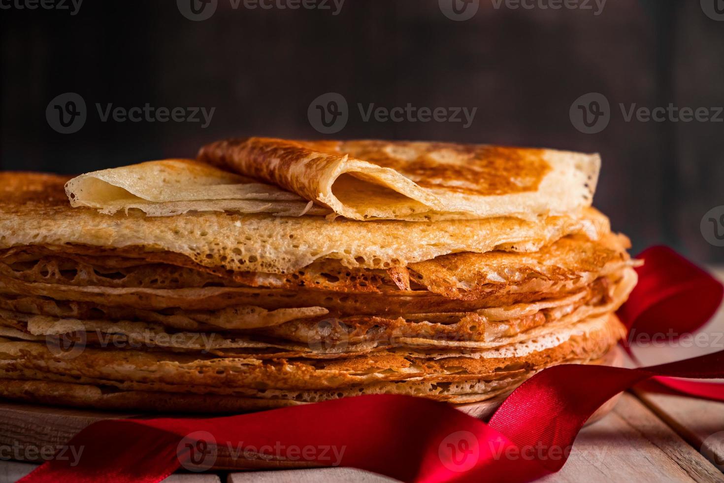 uma pilha de panquecas finas em um fundo escuro de madeira. um prato tradicional de crepes para o feriado maslenitsa. foto