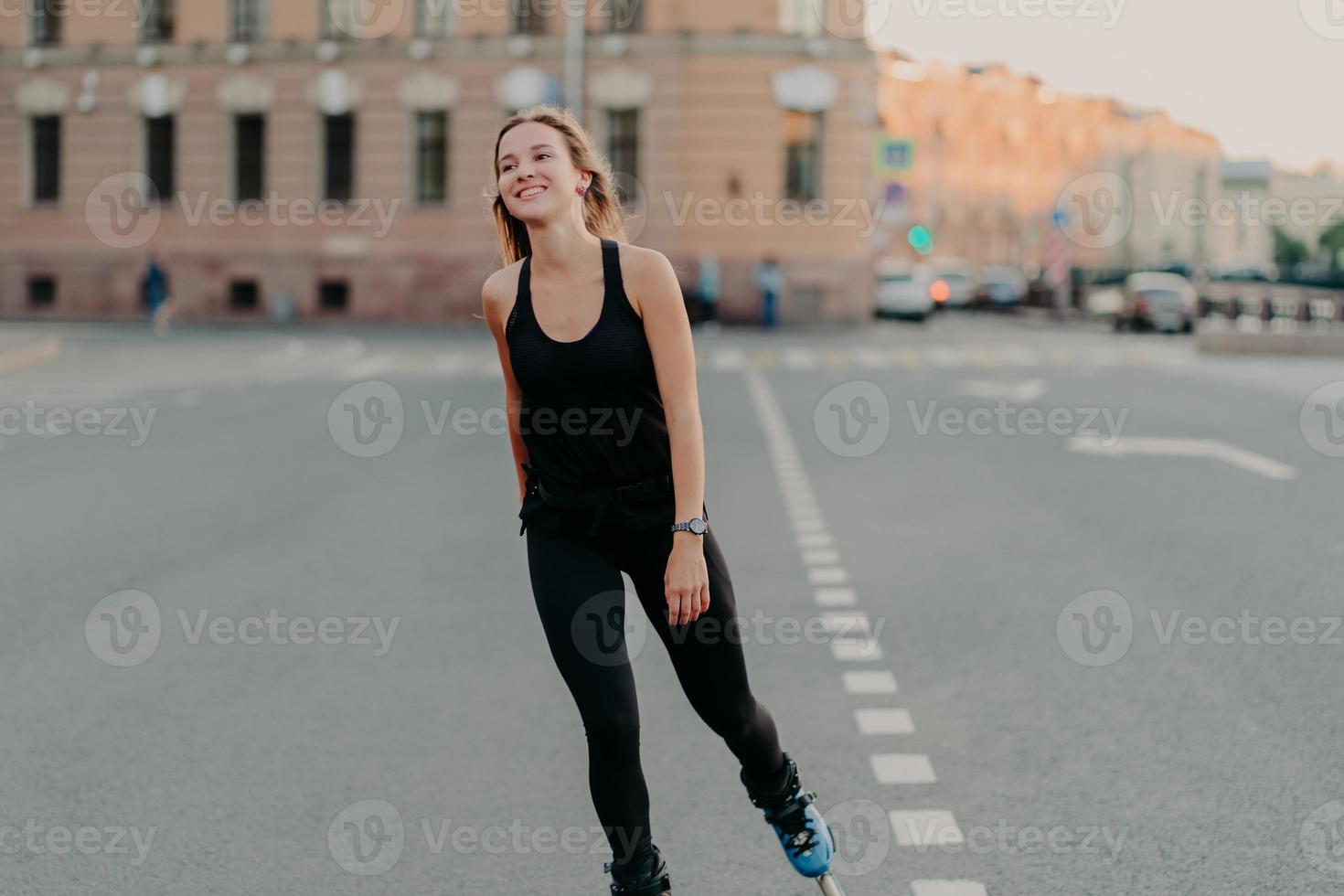 estilo de vida saudável verão lazer ativo conceito de recreação ao ar livre. jovem morena sorridente gosta de andar de patins enquanto o hobby olha para longe usa roupas esportivas anda rápido em rolos foto