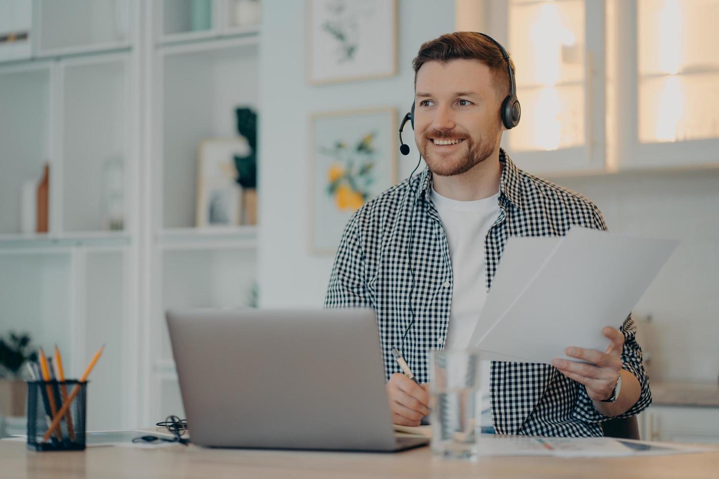 homem feliz segurando papéis durante a chamada online em casa foto