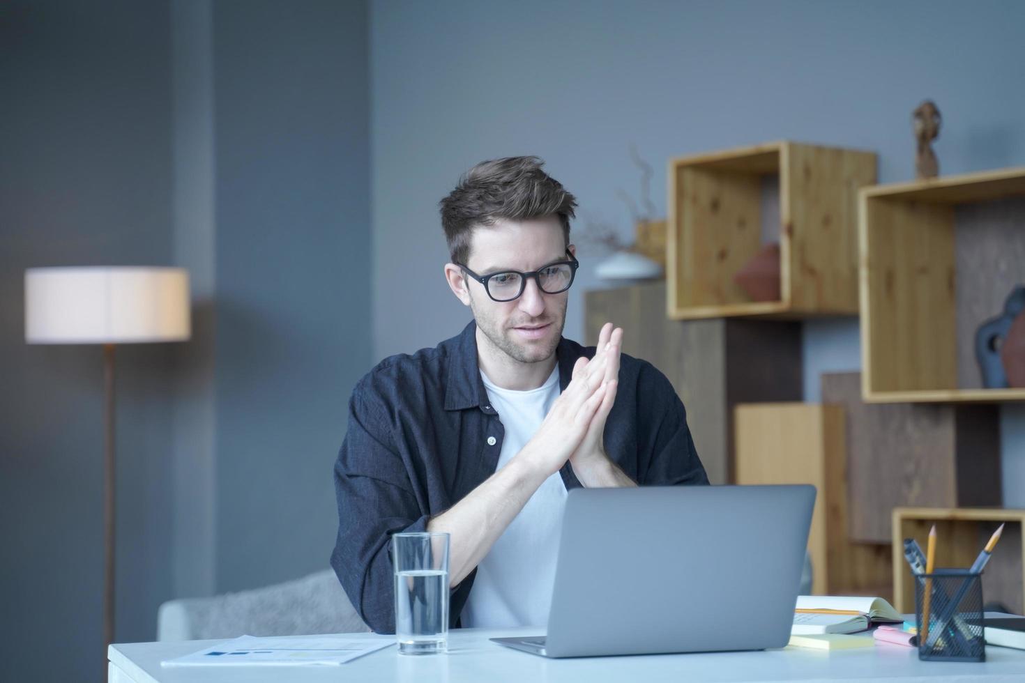 jovem austríaco bonito freelancer usando óculos olhando atentamente para a tela do computador foto