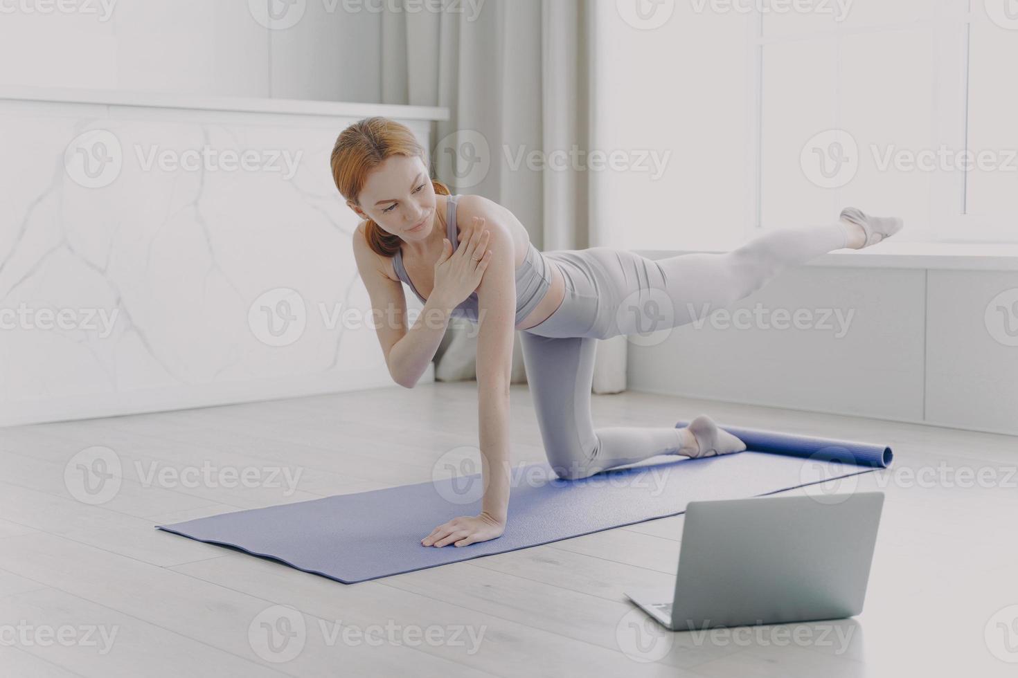 mulher treinadora tem vídeo aula. jovem atleta praticando ioga. treinamento pessoal por videoaulas. foto
