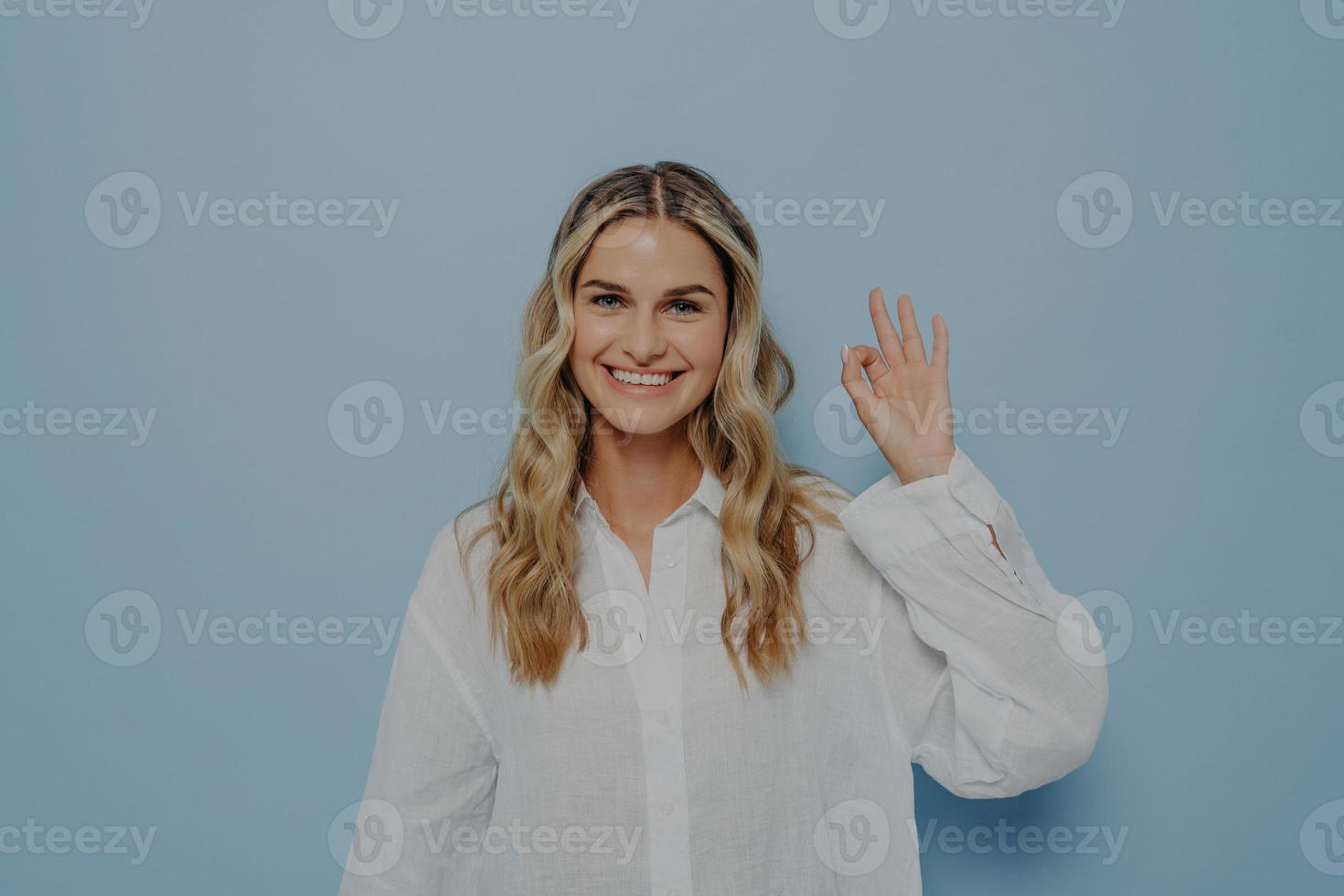 alegre mulher loira fazendo okey gesto com a mão foto