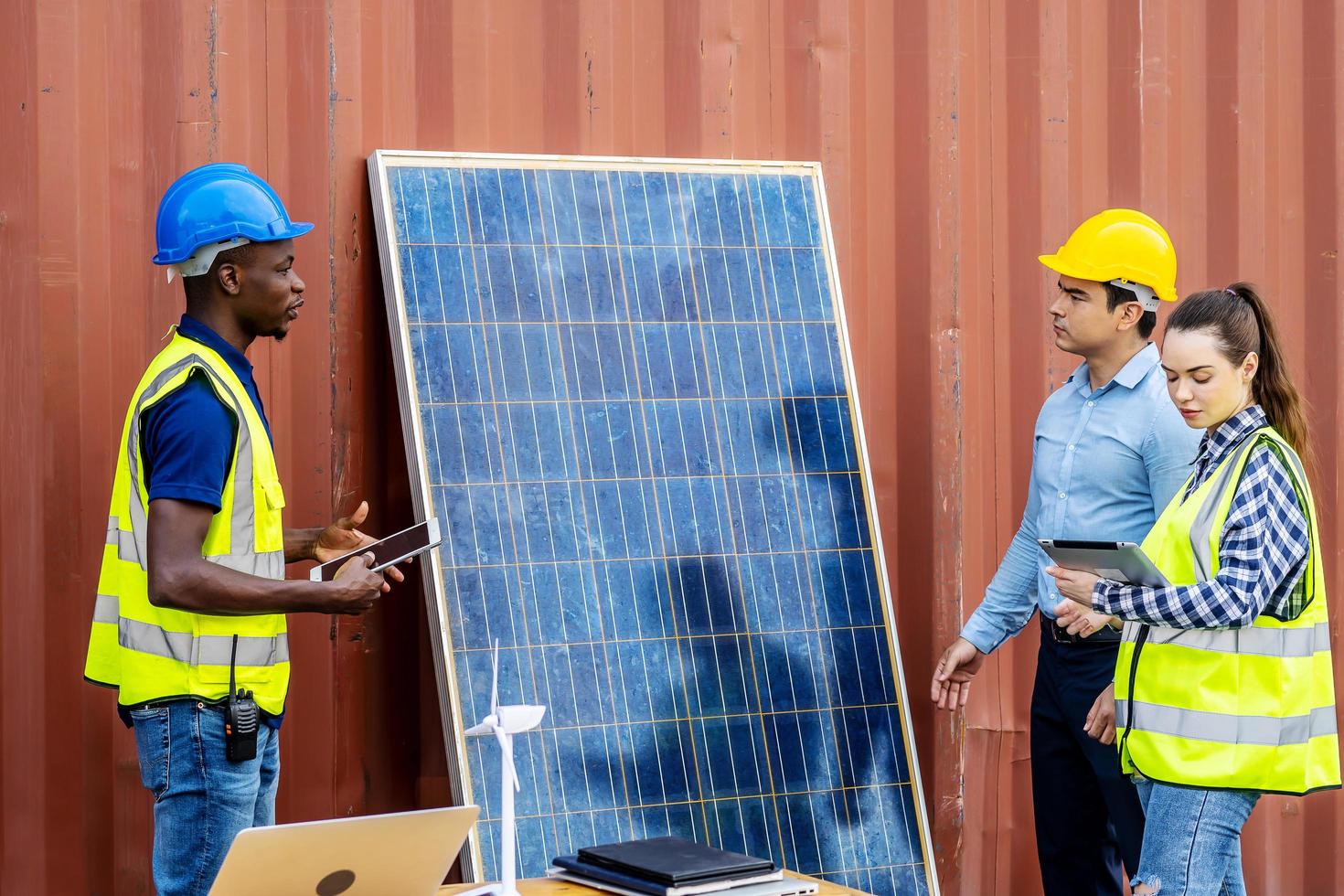 dois engenheiros de energia masculinos com sua equipe de colegas discutindo novo projeto prestes a investir na instalação de células solares fora do prédio ou fábrica industrial foto