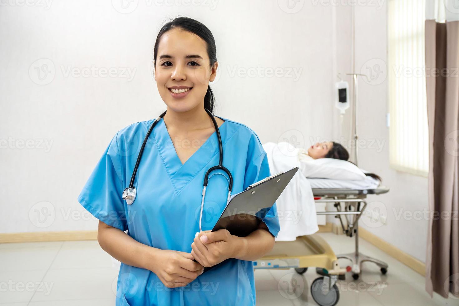 retrato de médica asiática sorridente confiante, enfermeira em pé sorrindo em uma camisa azul de laboratório segurando documentos do paciente na mão com estetoscópio, conceito de cuidados de saúde foto