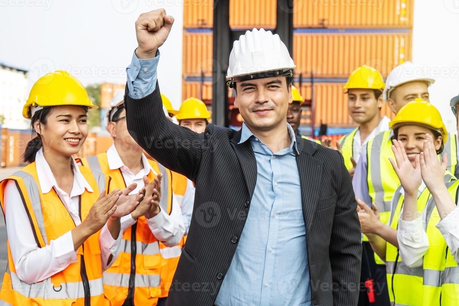 equipe profissional de engenharia e trabalhadores parabenizou o sucesso aplaudindo seu líder após a conclusão do projeto de construção e ele levantou sua mão alegremente foto