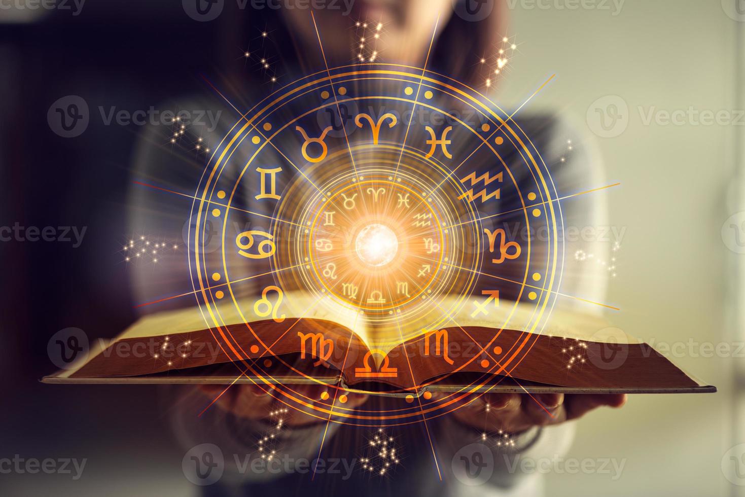 mulher segurando um livro de astrologia. projeção da roda astrológica, escolha um signo do zodíaco. conceito esotérico de astrologia. foto