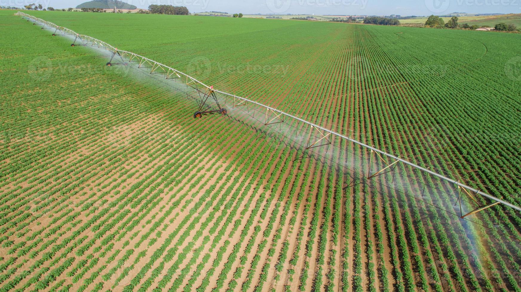 sistema de irrigação agrícola em dia ensolarado de verão. uma vista aérea de um sistema de sprinklers de pivô central. foto