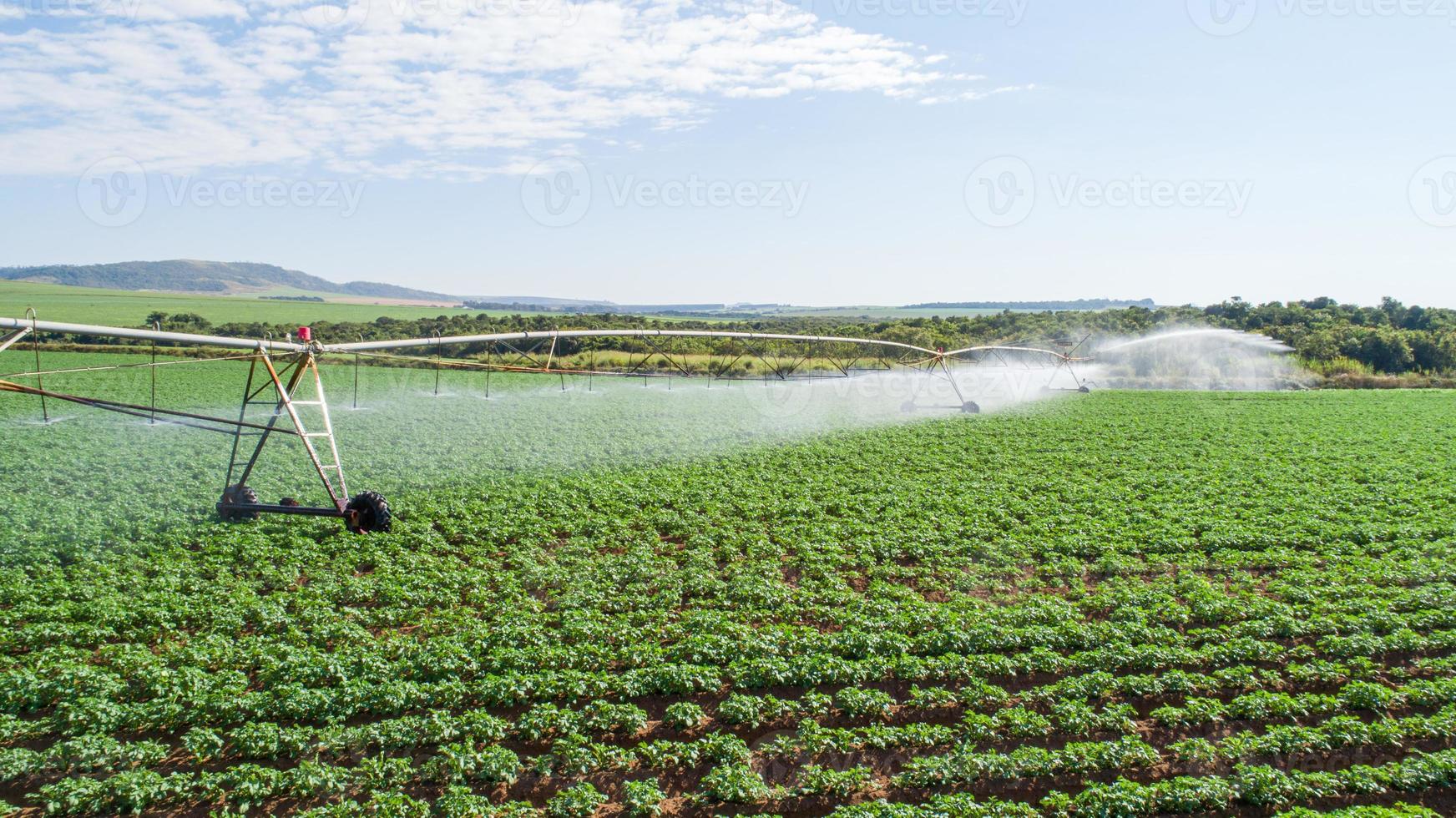 sistema de irrigação agrícola em dia ensolarado de verão. uma vista aérea de um sistema de sprinklers de pivô central. foto