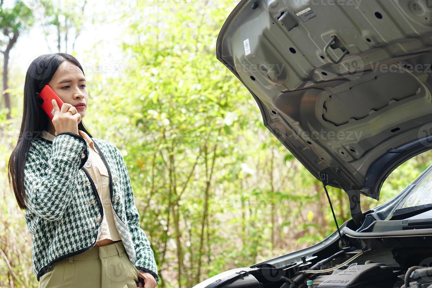 mulher asiática chama um mecânico, o carro sai na estrada ao redor da floresta. foto