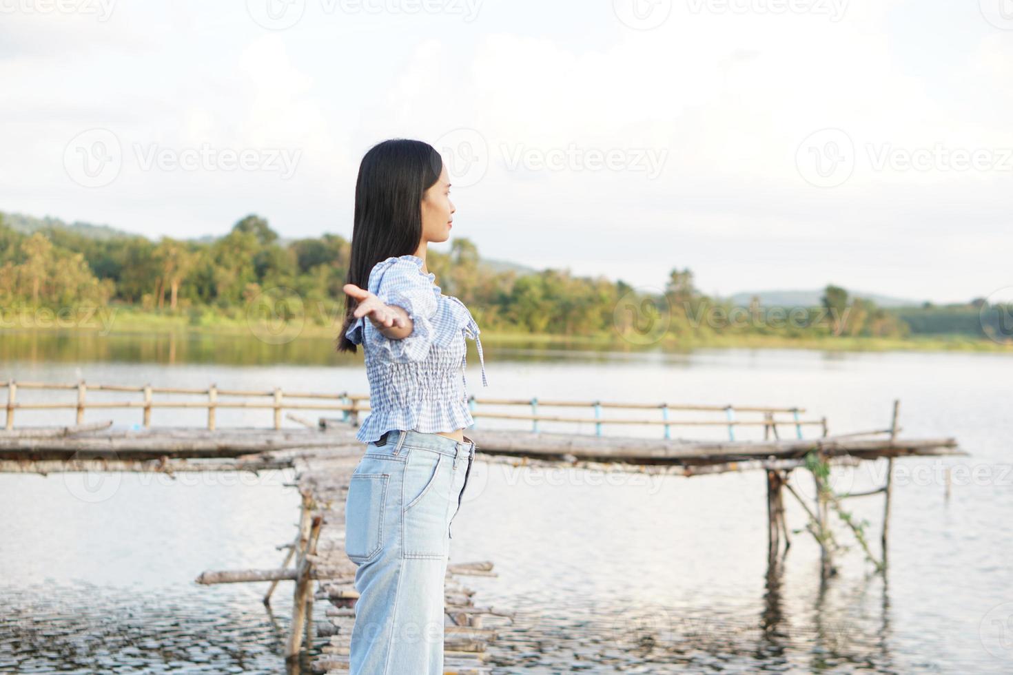 mulher asiática em um vestido azul claro está andando alegremente no meio do prado. foto