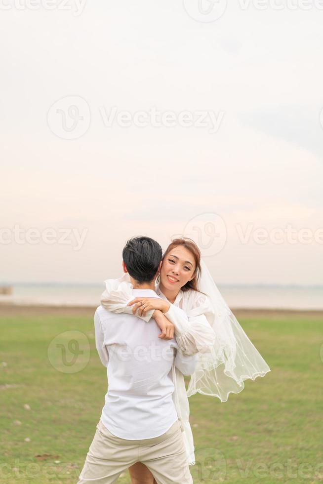 feliz jovem casal asiático em roupas de noivos foto