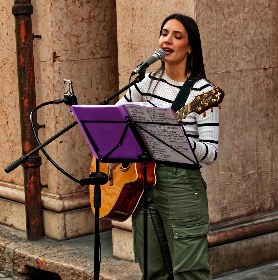 modena, itália, 10 de abril de 2022, músico feminino tocando violão e cantando ao ar livre no centro histórico de modena. tocando no conceito de rua. Itália foto