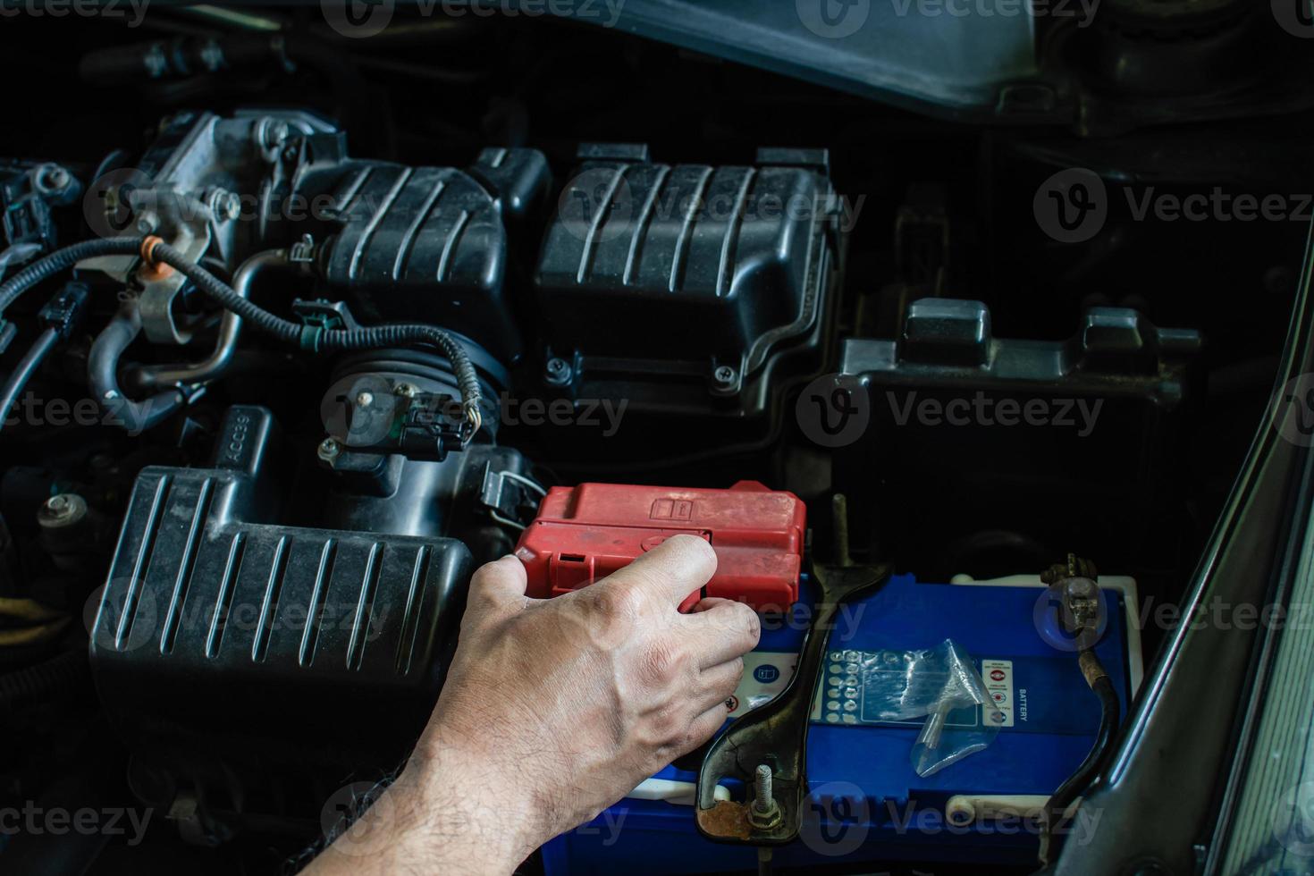 conceito de manutenção do motor. técnico está verificando o nível de energia da bateria. mão de homens estão examinando as principais fontes de energia e sistemas elétricos de seus carros. a alimentação CC falhou. fundo desfocado foto