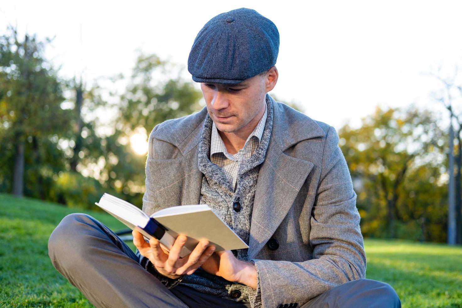 jovem hipster masculino ler livro no parque outono foto