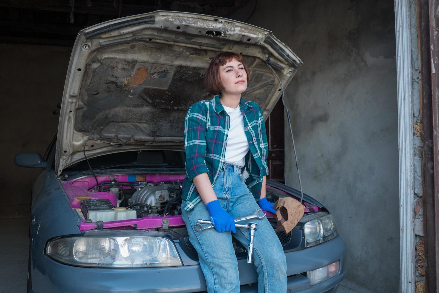 mecânico feminino consertando carro em uma garagem foto
