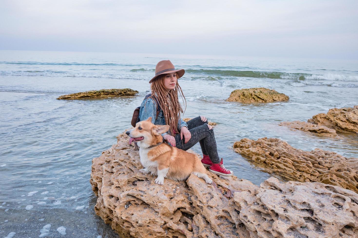 jovem mulher com cachorro corgi na praia foto