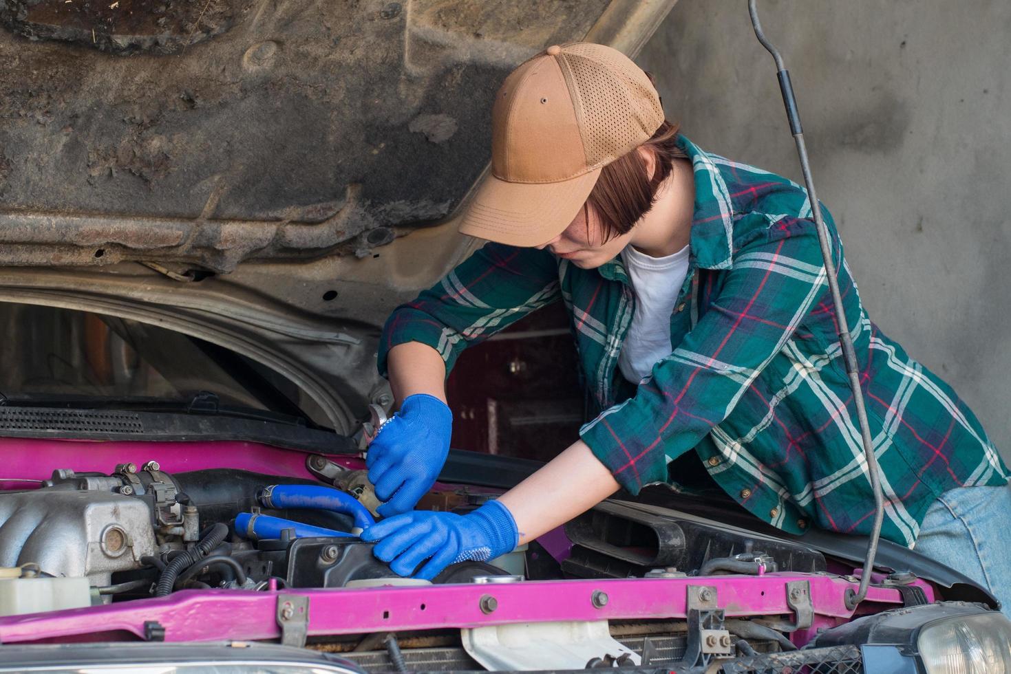 mecânico feminino consertando carro em uma garagem foto