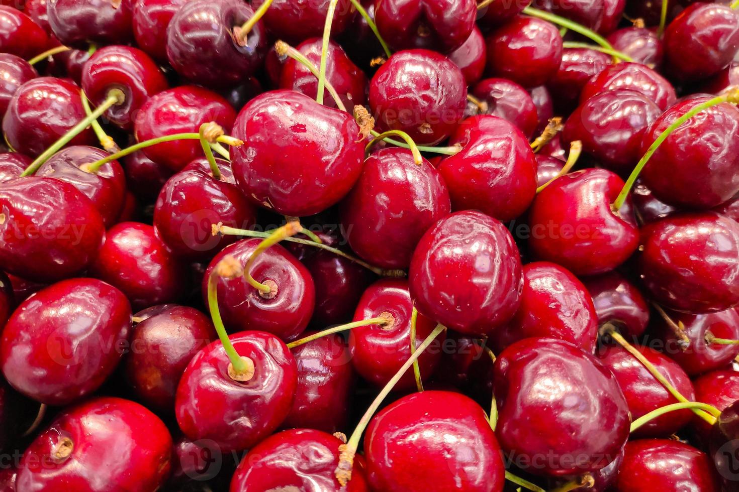 pilha de cerejas em uma banca de mercado foto