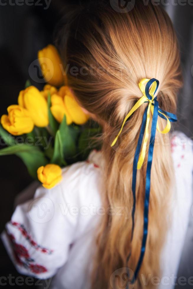 uma garotinha ucraniana em roupas tradicionais tem tulipas amarelas nas mãos foto