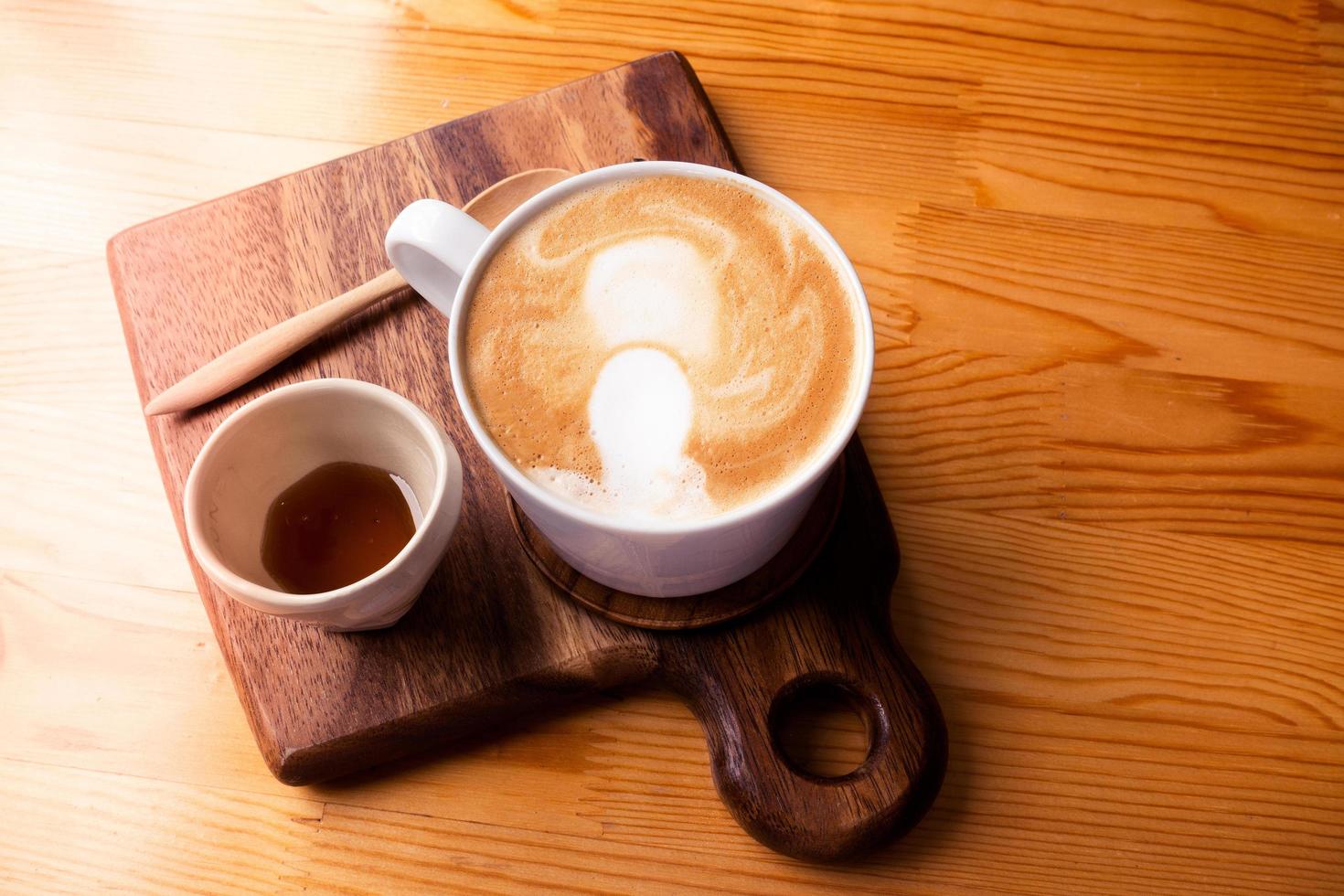 café com leite quente em uma xícara de café branca em uma mesa de madeira. foto